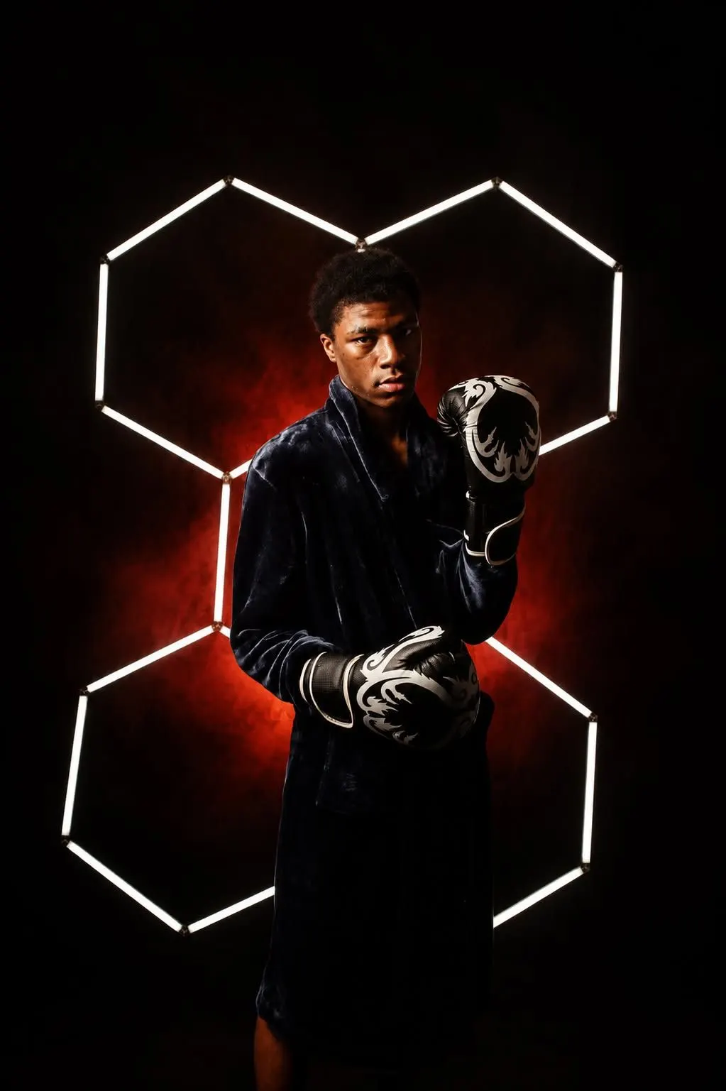 A teen boxer in a black robe and gloves framed by hexagon lights and red glow