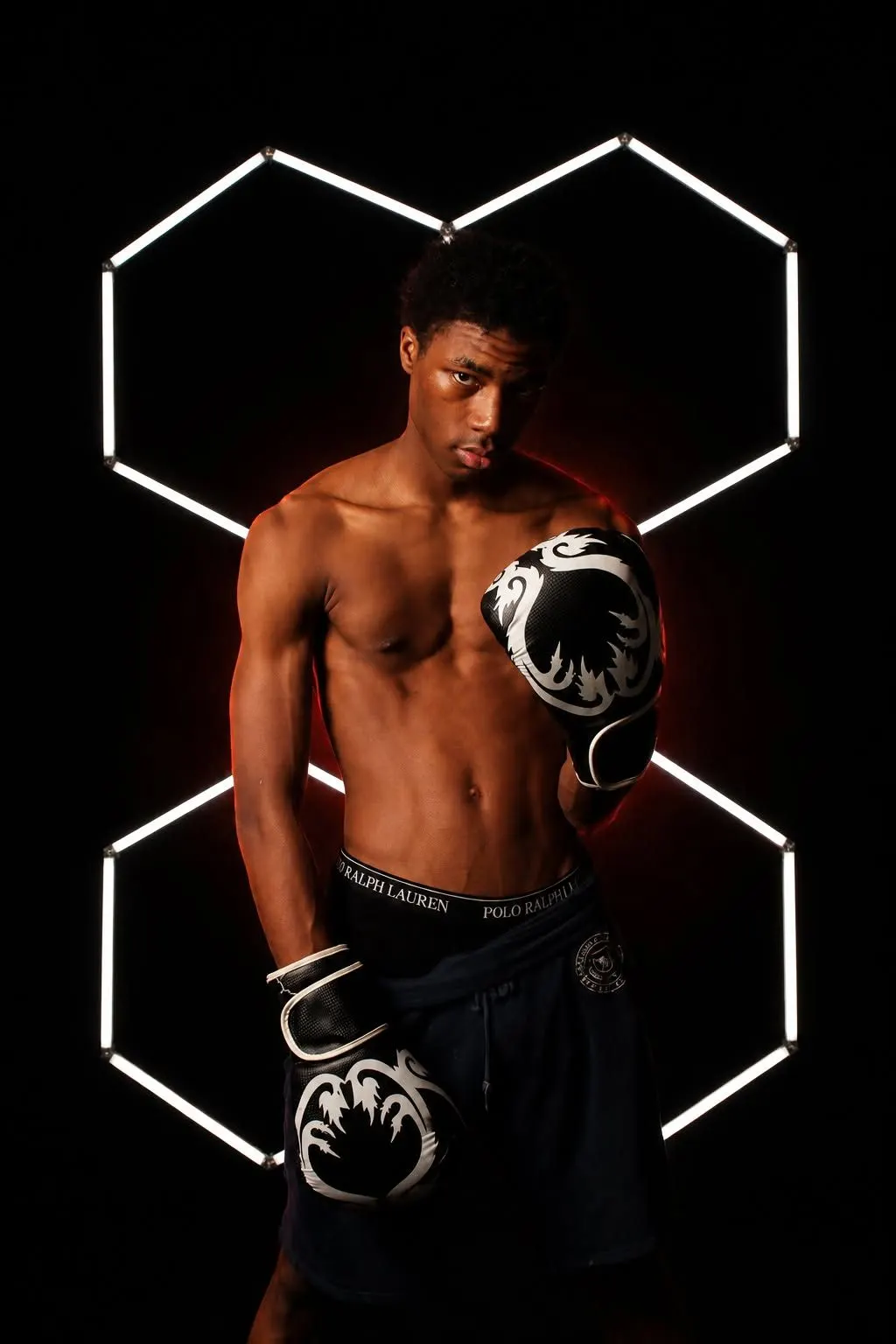 A young boxer with gloves standing inside a glowing hexagon light frame