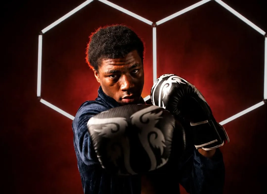 Close-up of a young boxer behind his gloves with hexagon lights behind