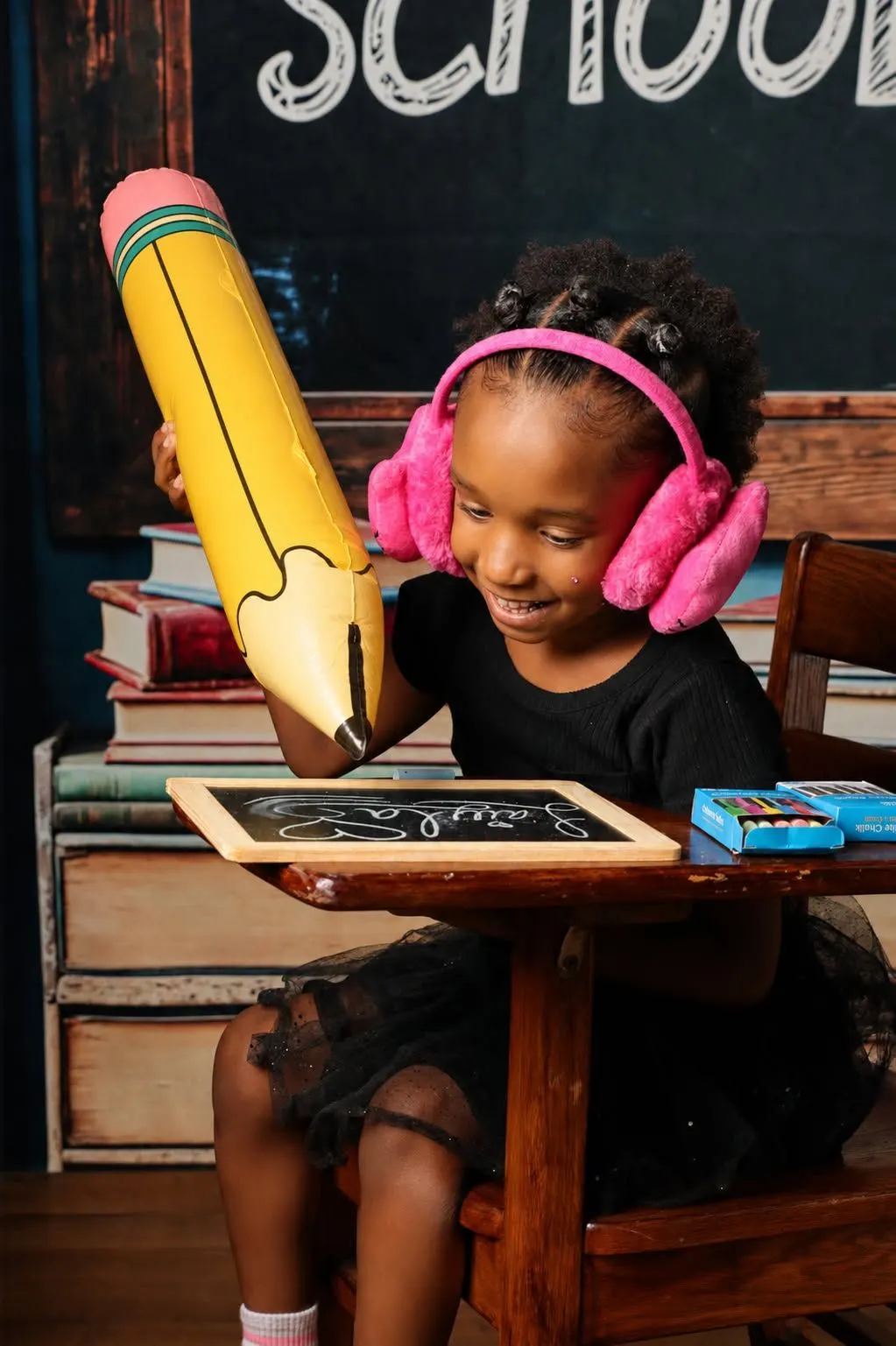 A girl with pink headphones at a school desk on the back-to-school set