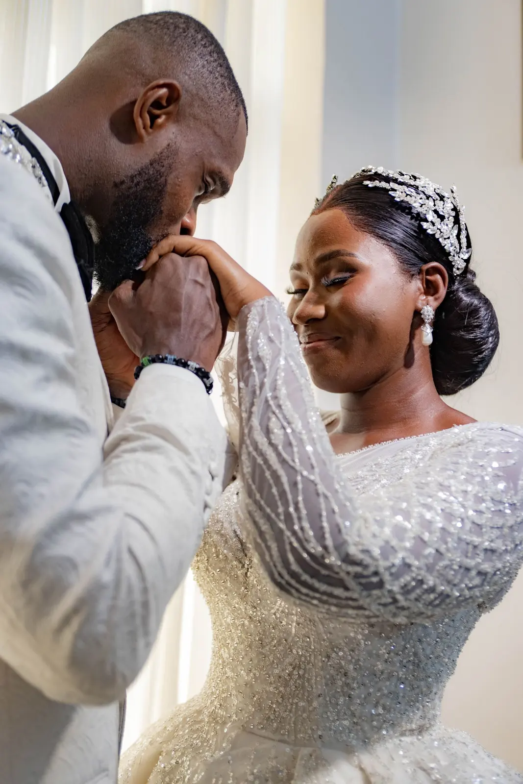 A groom kissing his bride’s hand as she smiles